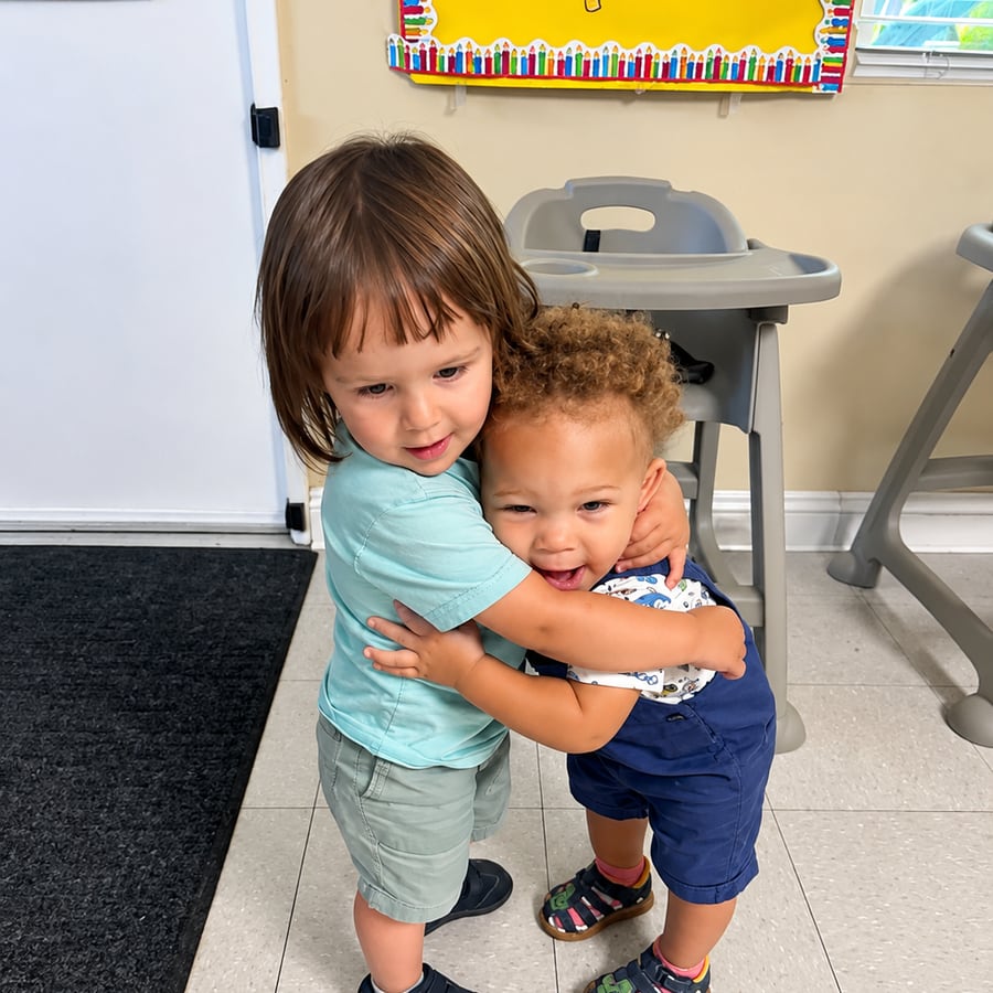 Two toddlers hugging each other in the classroom