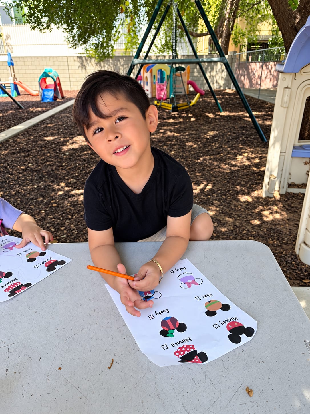 A boy smiling at the picnic table with his Disney character worksheet